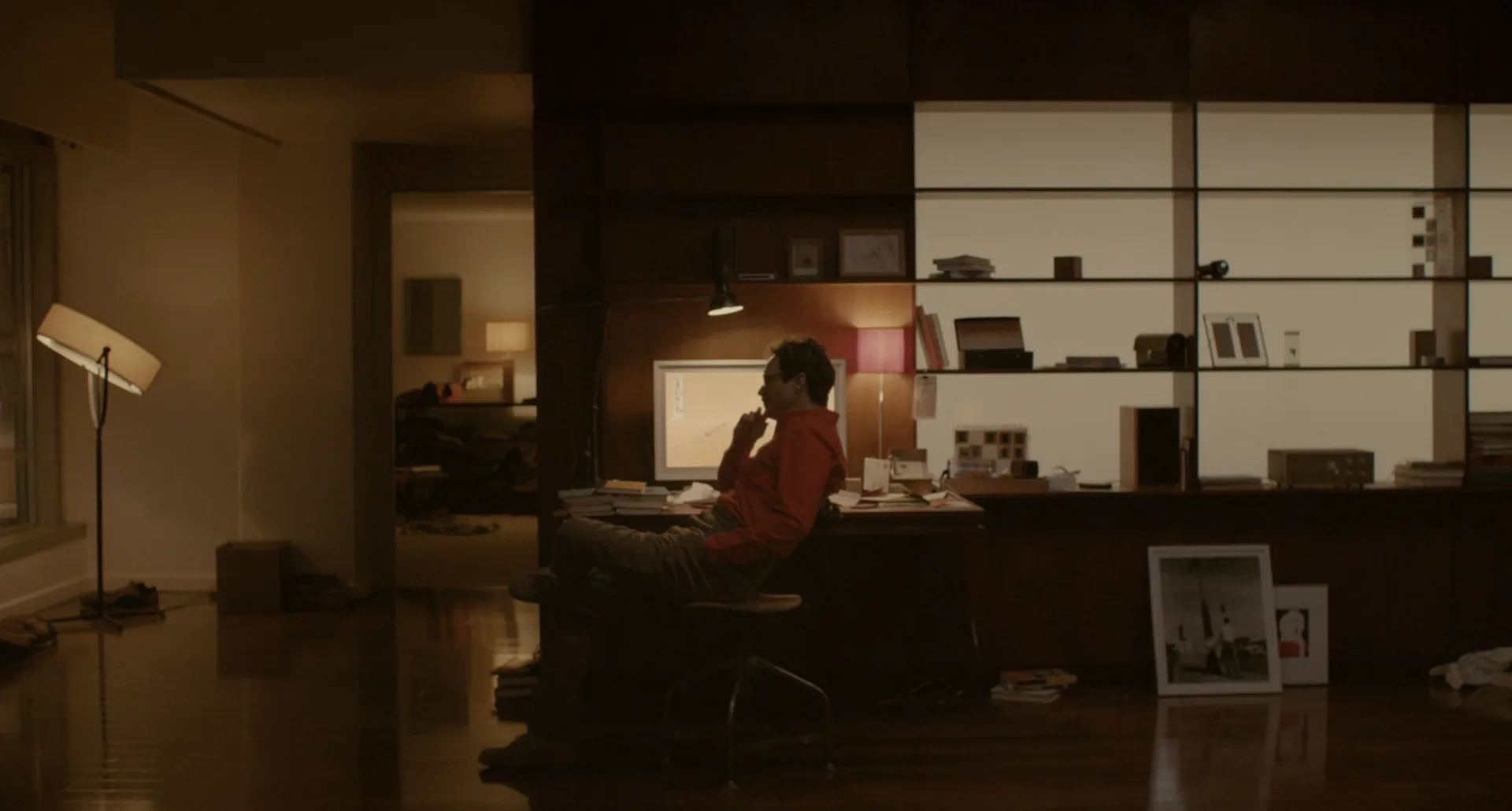 Theodore solo en su departamento, sentado frente al escritorio de noche, en la película Her