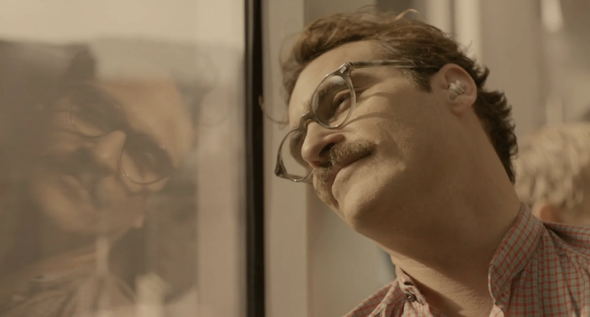 Theodore recostado contra un vidrio, con su reflejo al lado, en la película Her