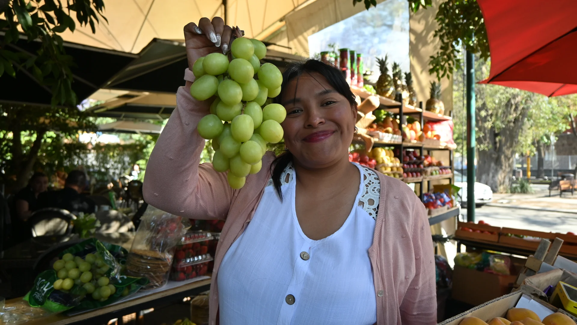 Sthefany Bonifacio sostiene un racimo de uvas verdes en su puesto de la Frutería Pepe