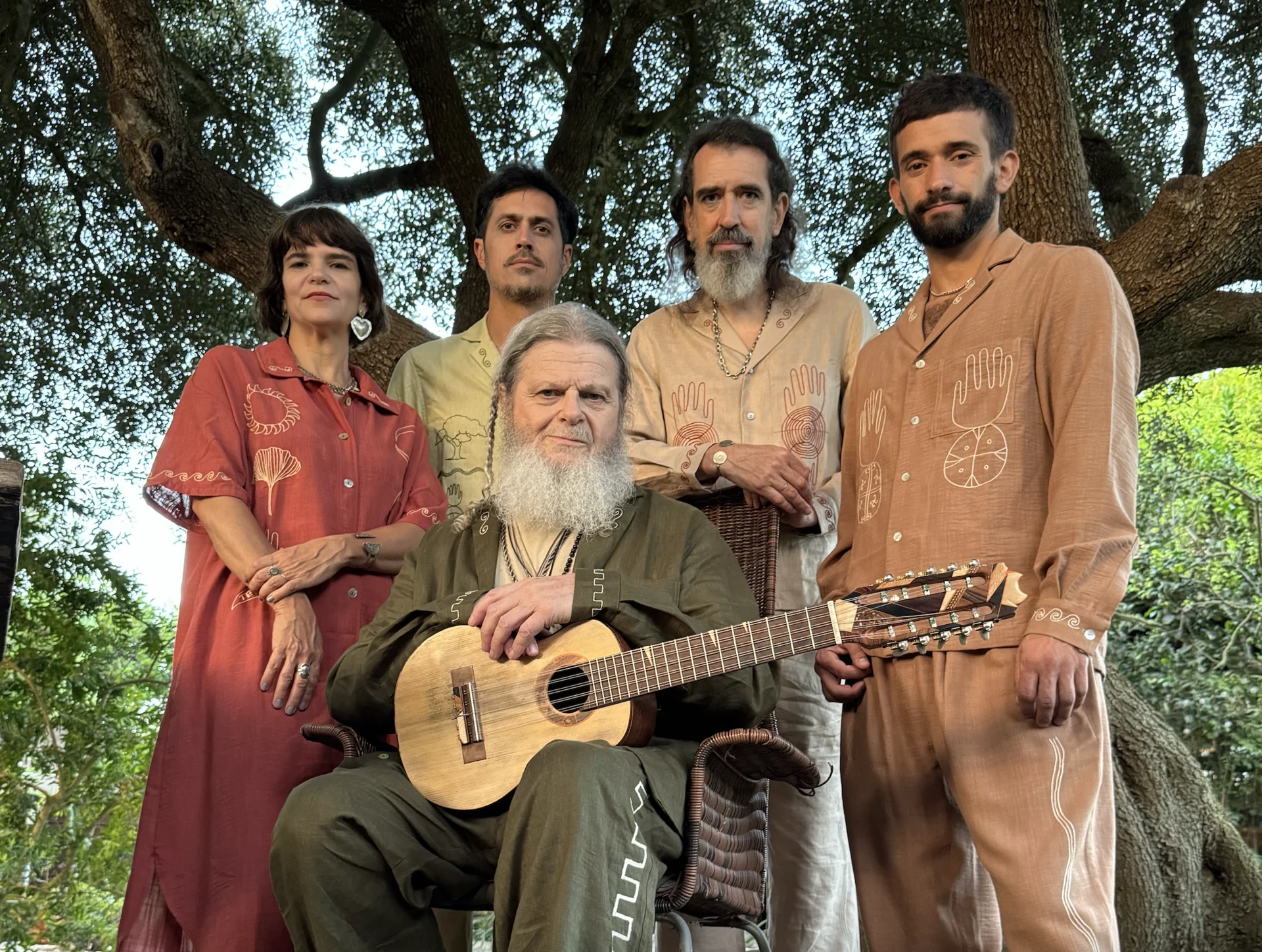 Santaolalla con los miembros de su banda del Ronroco Tour bajo un árbol grande, todos vestidos con camisas con bordados latinoamericanos